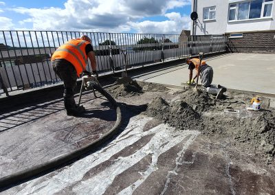 Contractors applying floor screed material to a garage roof