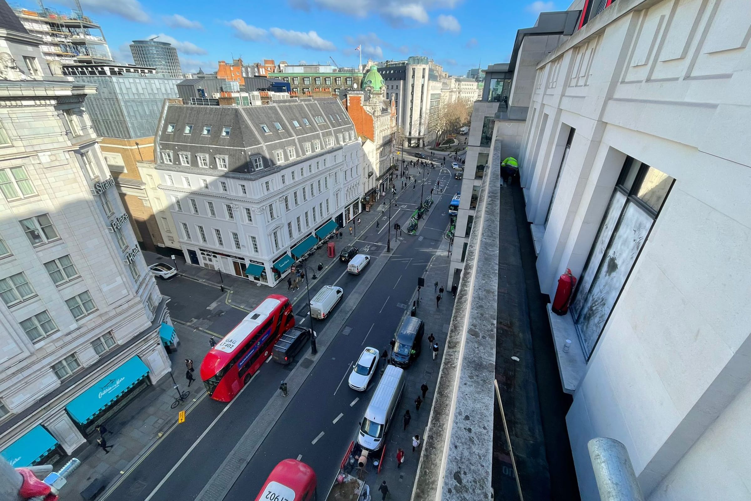 Floor screeding in central London View down onto a busy London street showing road an the top of a red bus with worker installing floor screed onto a narrow ledge