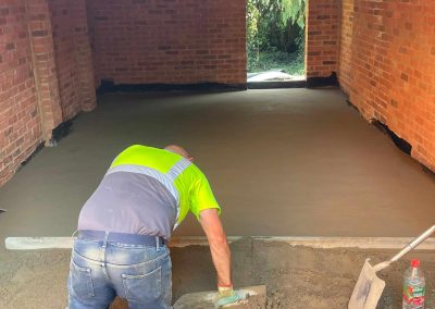 Floor screeding contractor using a straight edge to accurately apply floor screed material and create a perfectly level floor surface