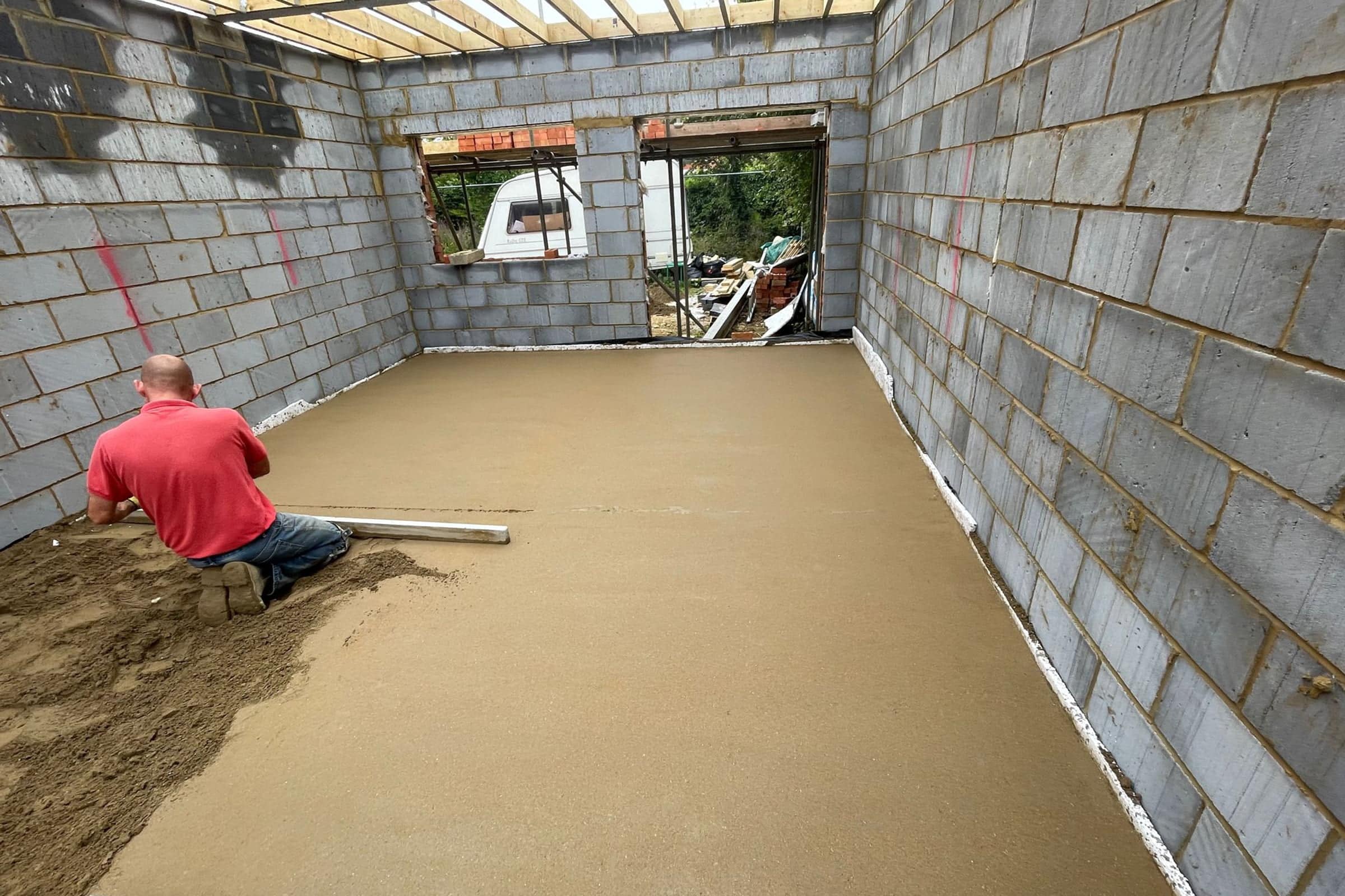 Floor screeding at new build in Northampton Contractor using a straight edge to accurately apply floor screed material and create a perfectly level floor surface in a new build property