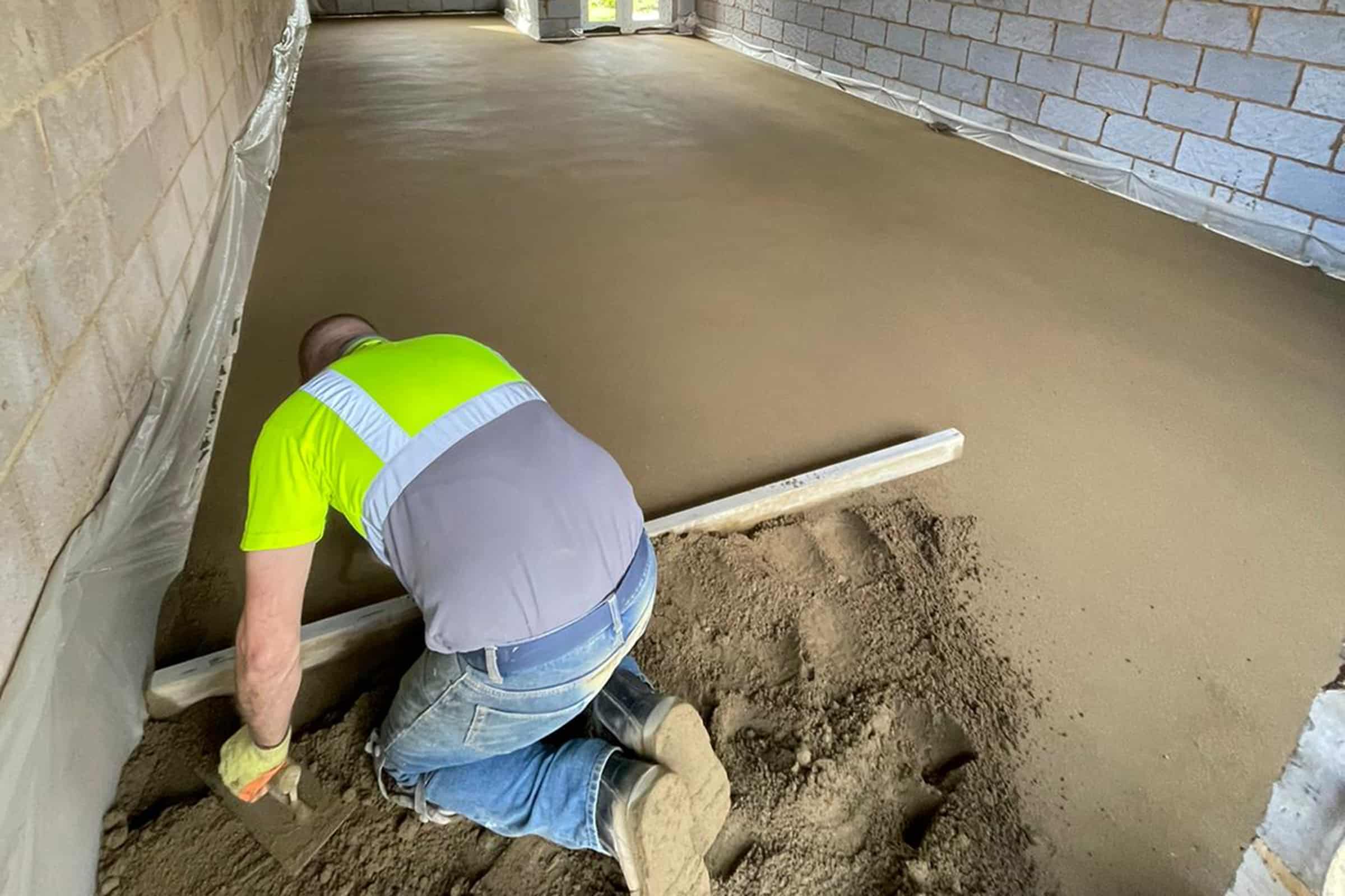 Floor screeding at a new build development in Northampton Contractor using a straight edge to accurately apply floor screed material and create a perfectly level floor surface for a home extension