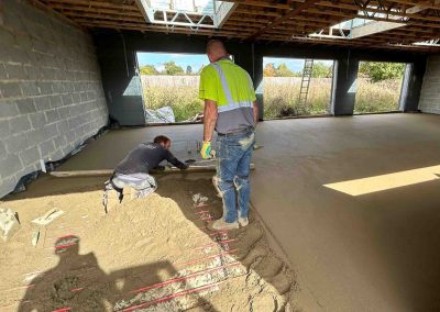 Contractor using a straight edge to accurately apply floor screed material and create a perfectly level floor surface for a home extension