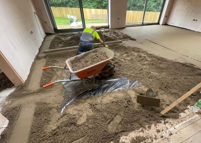 Contractor using a straight edge to accurately apply floor screed material and create a perfectly level floor surface