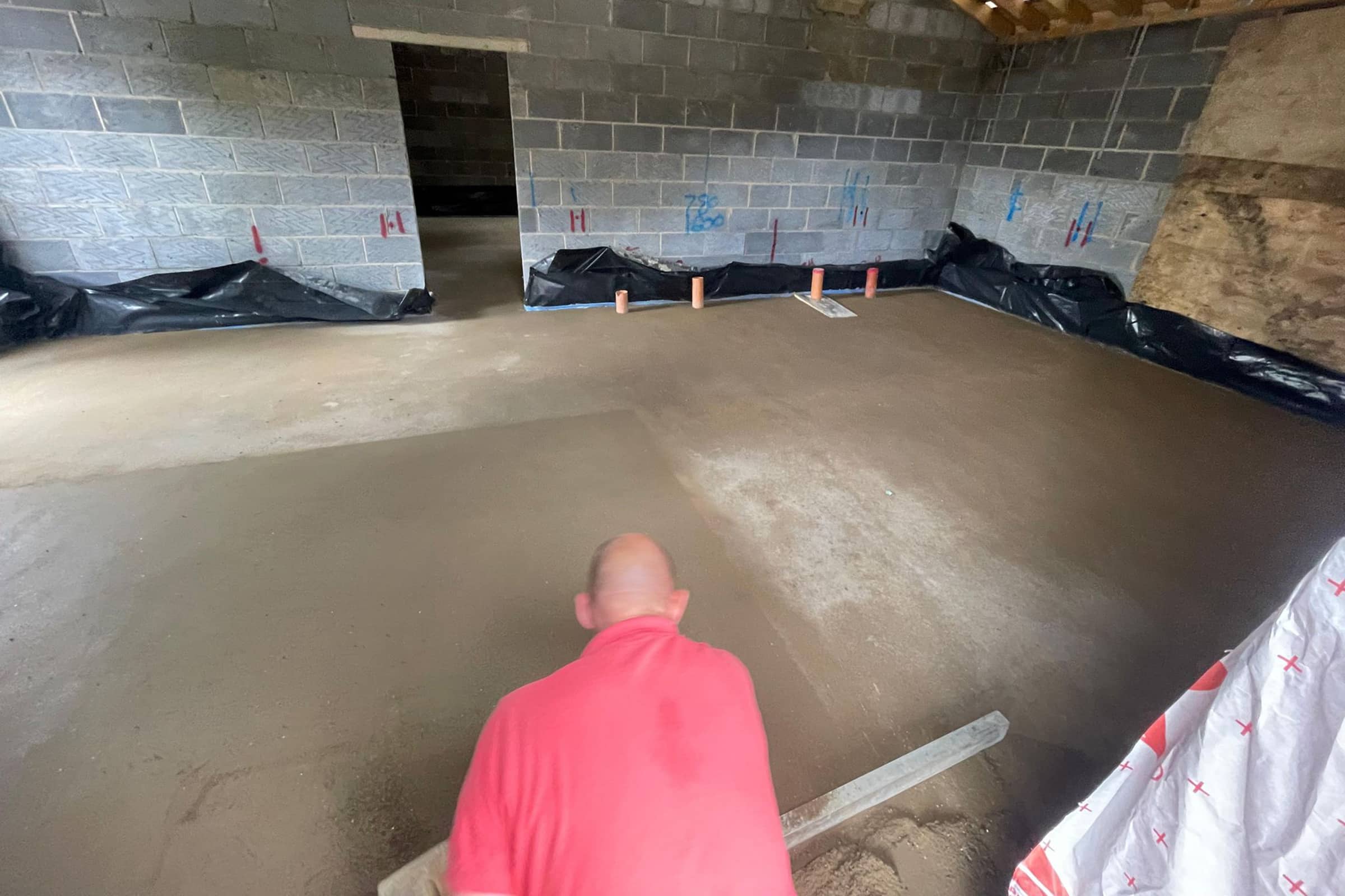 Floor screeding contractor using a straight edge to accurately apply floor screed material and create a perfectly level floor surface
