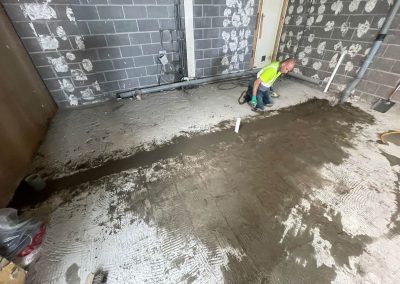Worker installing a floor screed surface at a retail unit