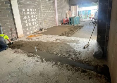 Worker installing a floor screed surface at a retail unit