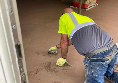 Floor screeding contractor using a trowel to accurately smooth floor screed material and create a perfectly level floor surface