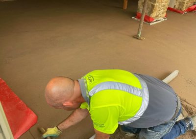 Floor screeding contractor using a trowel to accurately smooth floor screed material and create a perfectly level floor surface