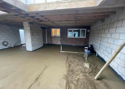 Contractor using a straight edge to accurately apply floor screed material and create a perfectly level floor surface for a home extension