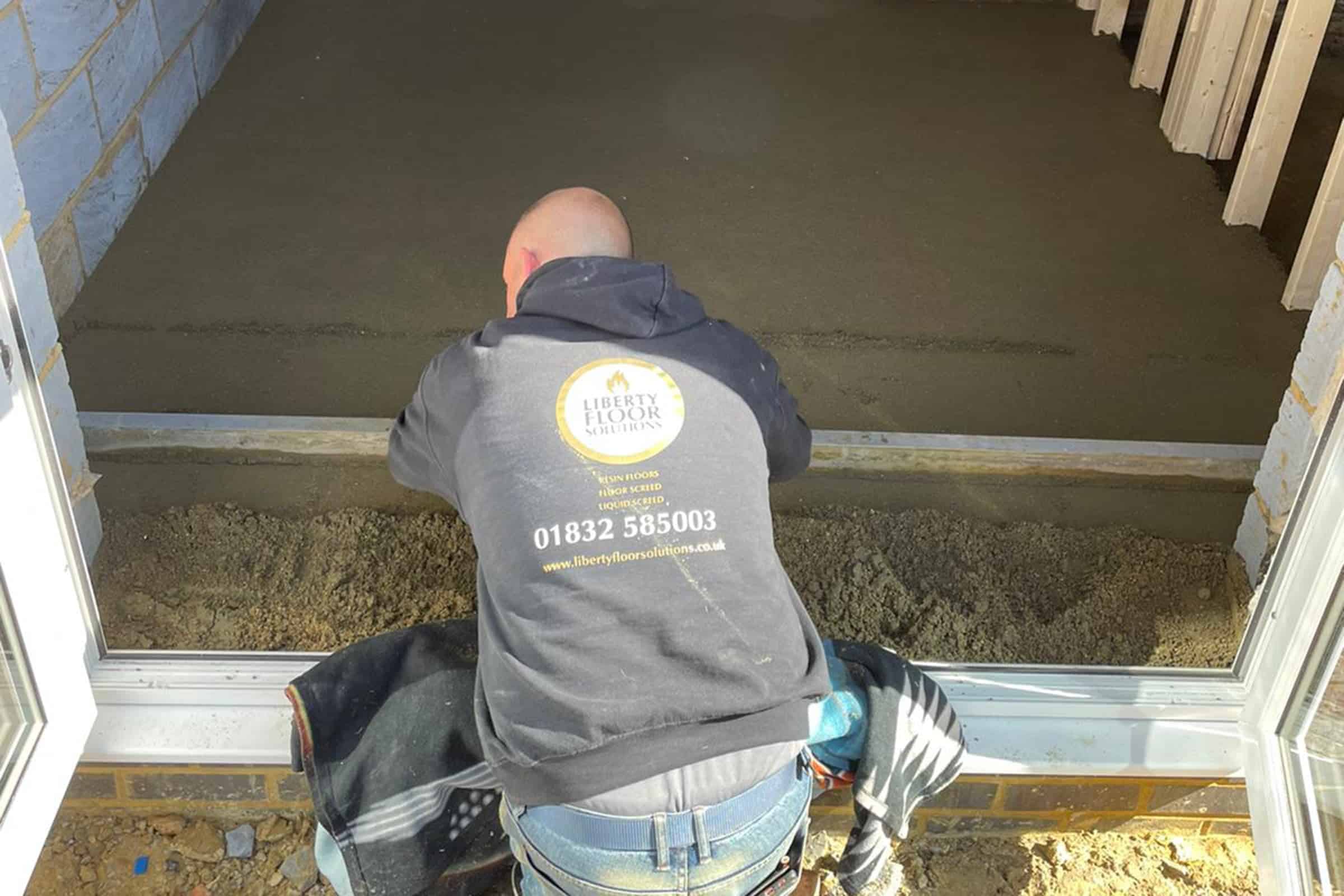 Floor screeding at a small home extension in Moulton, Northampton Contractor using a straight edge to accurately apply floor screed material and create a perfectly level floor surface