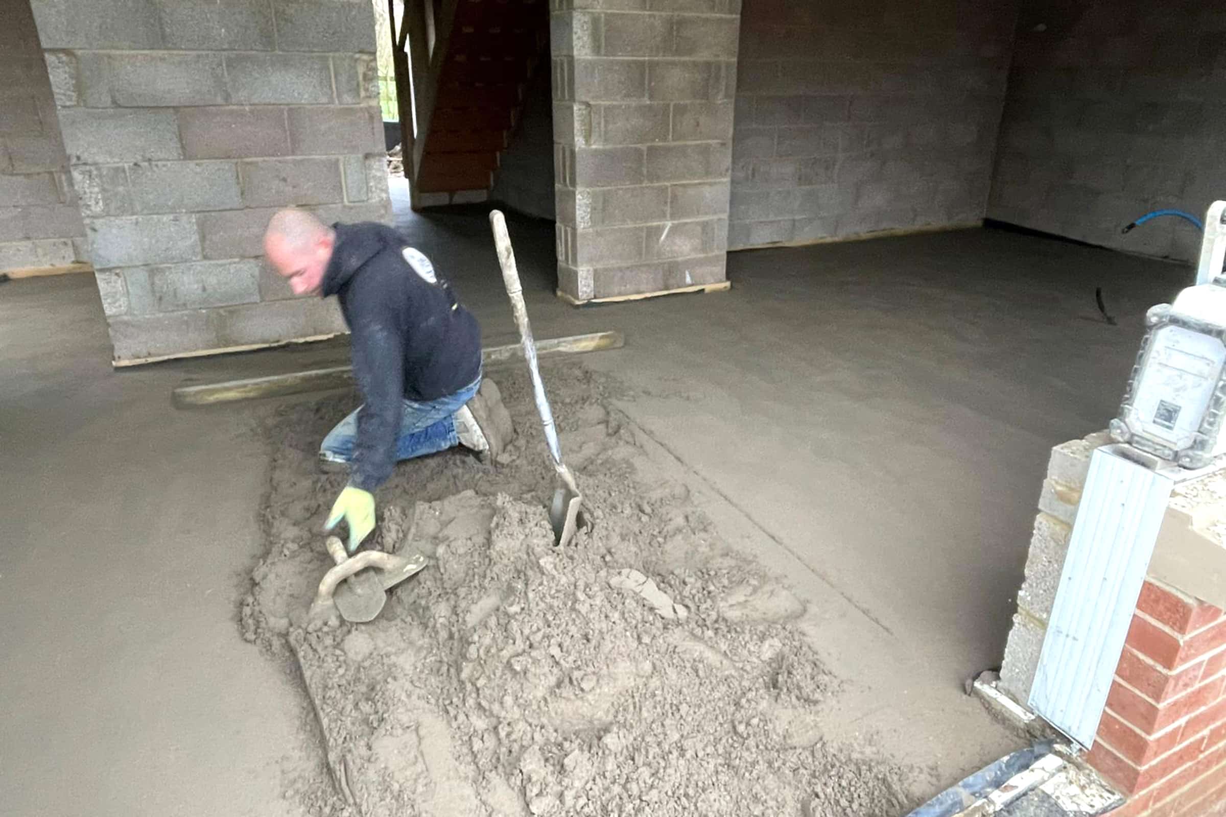 Floor screeding contractor using a trowel to create a perfectly level floor surface