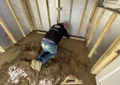 Floor screeding contractor using a straight edge to accurately apply floor screed material and create a perfectly level floor surface