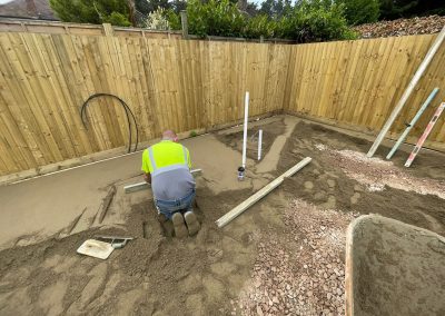Contractor using a straight edge to accurately apply floor screed material and create a perfectly level floor surface for a patio area