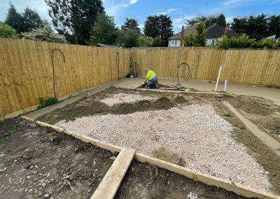 Contractor using a straight edge to accurately apply floor screed material and create a perfectly level floor surface for a patio