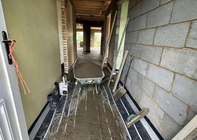 Underfloor heating pipes laid out at a home extension project with partially completed floor screed