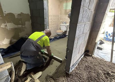 Contractor using a straight edge to accurately apply floor screed material and create a perfectly level floor surface for a home extension