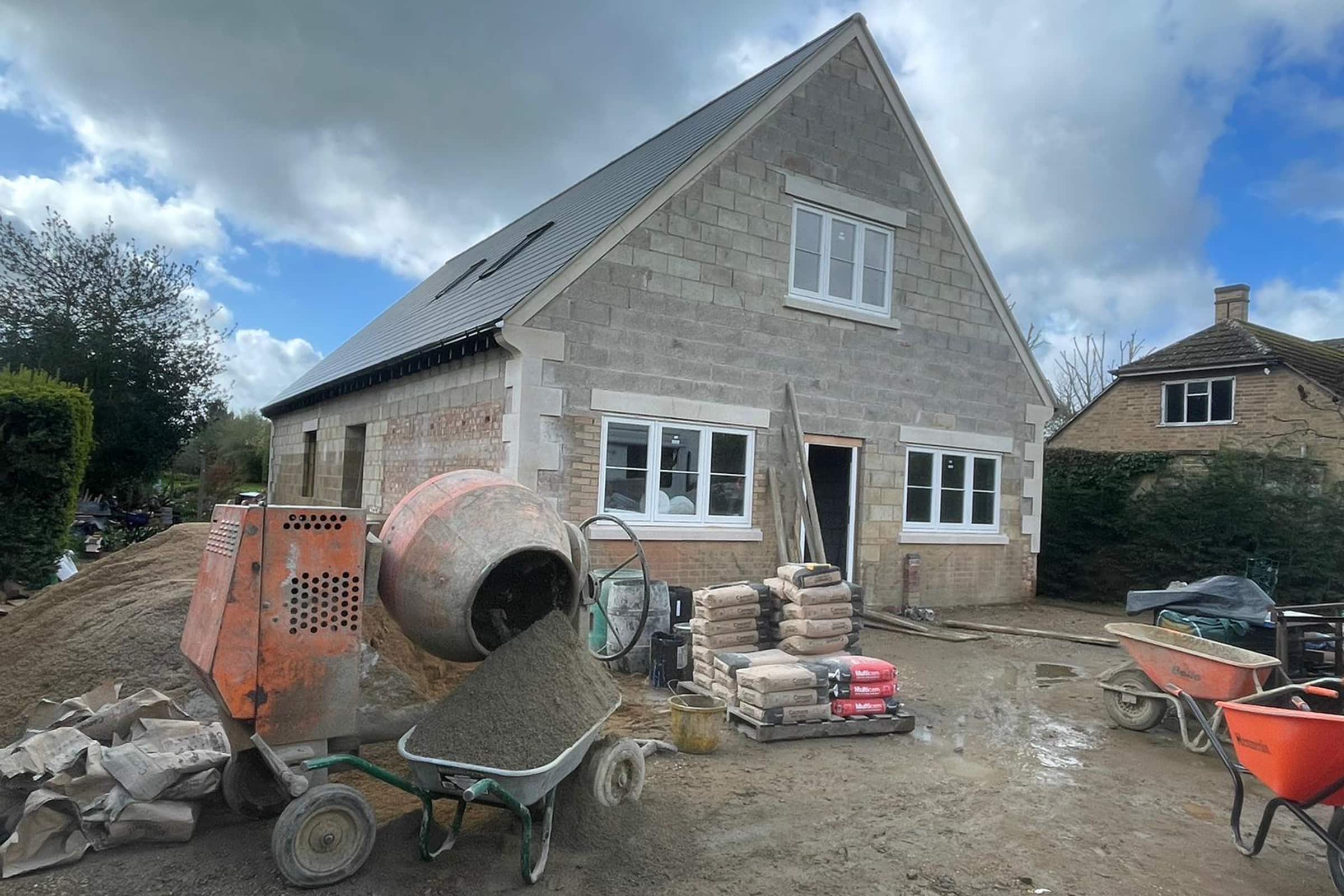 Exterior of a new build property with cement mixer and floor screed materials