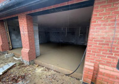 Newly installed floor screed surface in an open fronted double garage