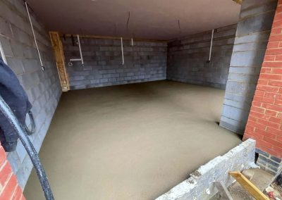Newly installed floor screed surface in an open fronted double garage