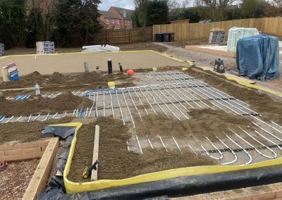 Underfloor heating pipes laid out at a open air new build plot with partially completed floor screed