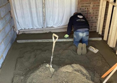 Contractor using a straight edge to accurately apply floor screed material and create a perfectly level floor surface