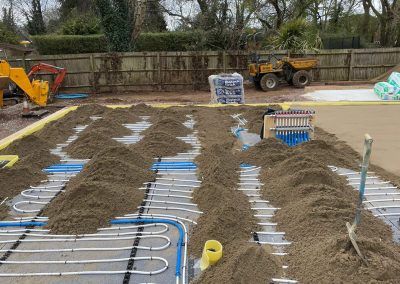Underfloor heating pipes laid out at a open air new build plot with partially completed floor screed