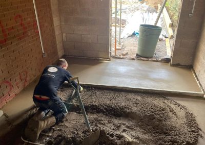 Floor screeding contractor using a straight edge to accurately apply floor screed material and create a perfectly level floor surface