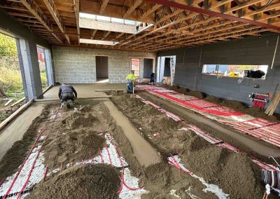 Workers and underfloor heating pipes laid out at a new build property with partially completed floor screed