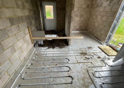 Underfloor heating pipes laid out at a home extension project with partially completed floor screed