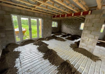 Underfloor heating pipes laid out at a home extension project with partially completed floor screed