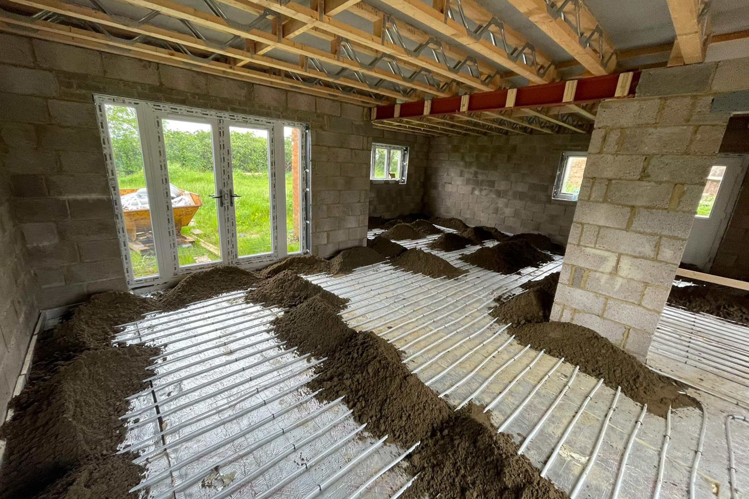 Underfloor heating pipes laid out at a home extension project with partially completed floor screed